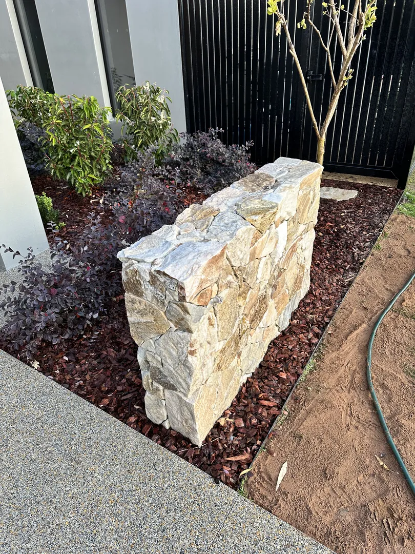 Stone garden wall in landscaped yard.